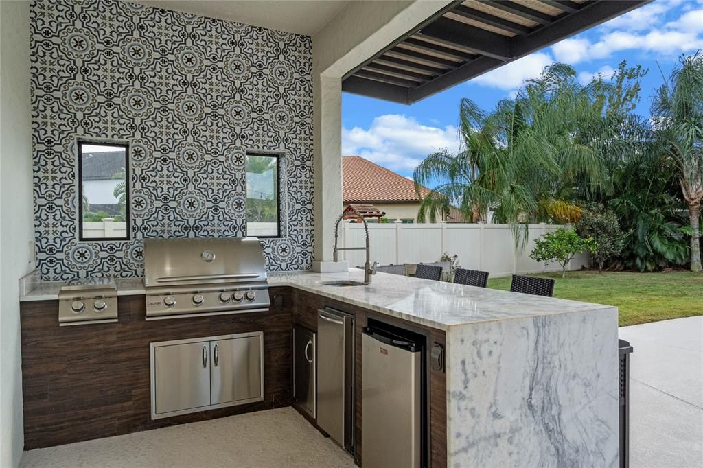 Outdoor kitchen area with Blaze grill, fridge, ice-maker and sink area.