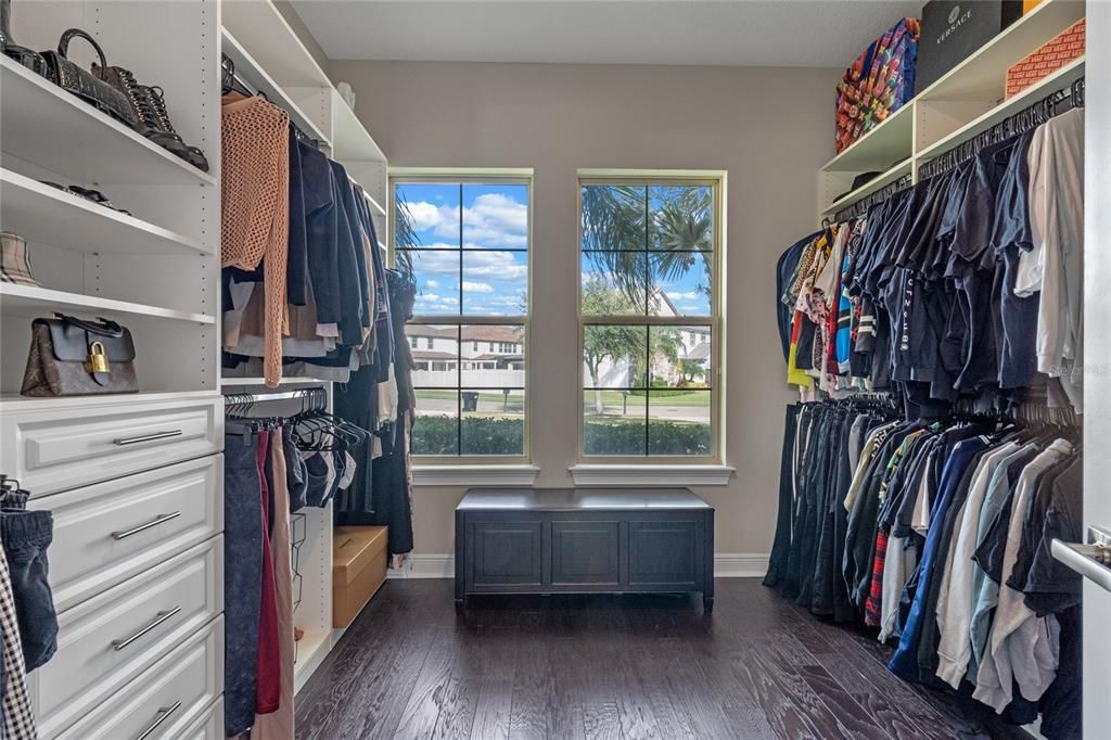 The primary bedroom closet features custom built in cabinetry