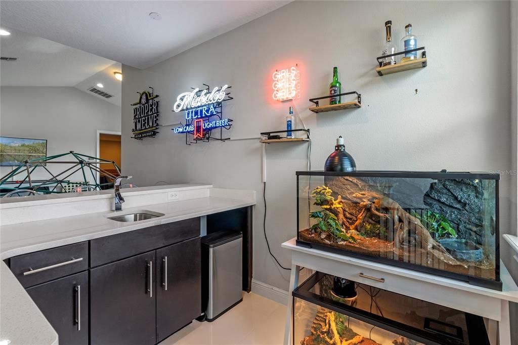 The home bar features wood cabinets, quartz counters and space for a wine cooler or fridge.