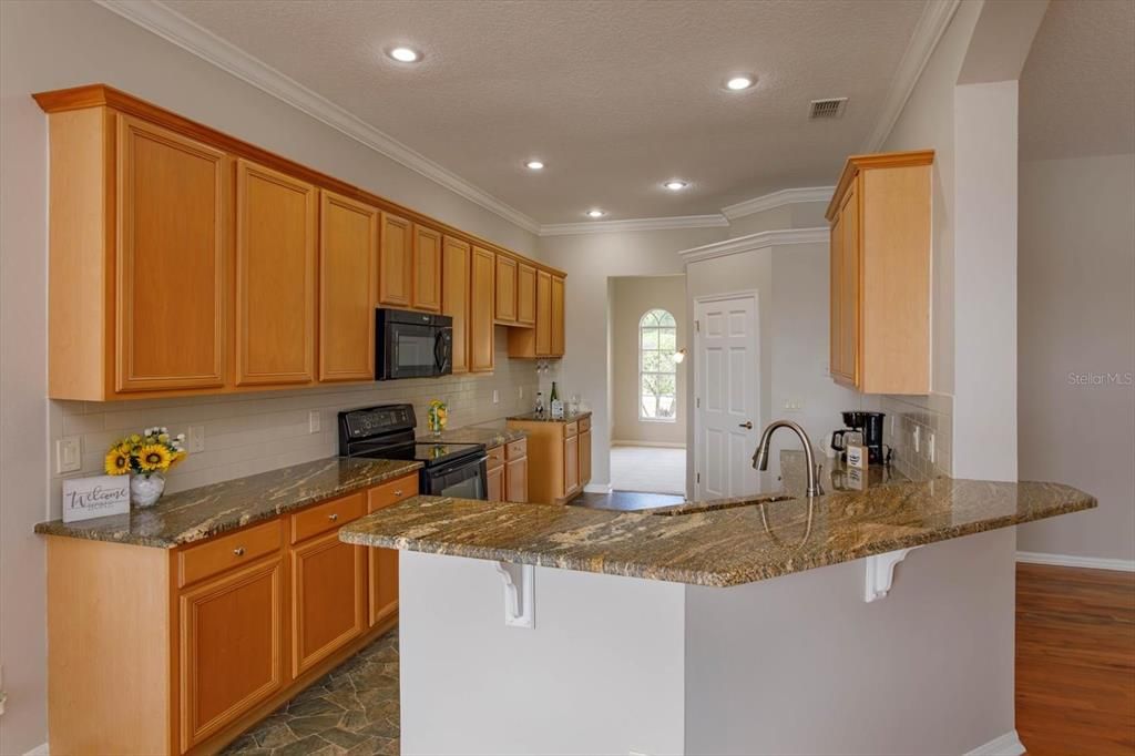 Open kitchen features exotic granite counters and crown molding