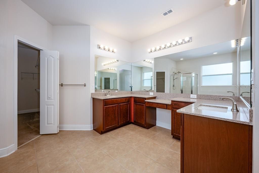 A tranquil retreat for the homeowner there is direct access to the lanai/pool and behind double doors a private en-suite bath that boasts DUAL/WALK-IN CLOSETS, a wrap around vanity with two sinks, space for seating and endless storage, a SOAKING TUB and glass enclosed shower.