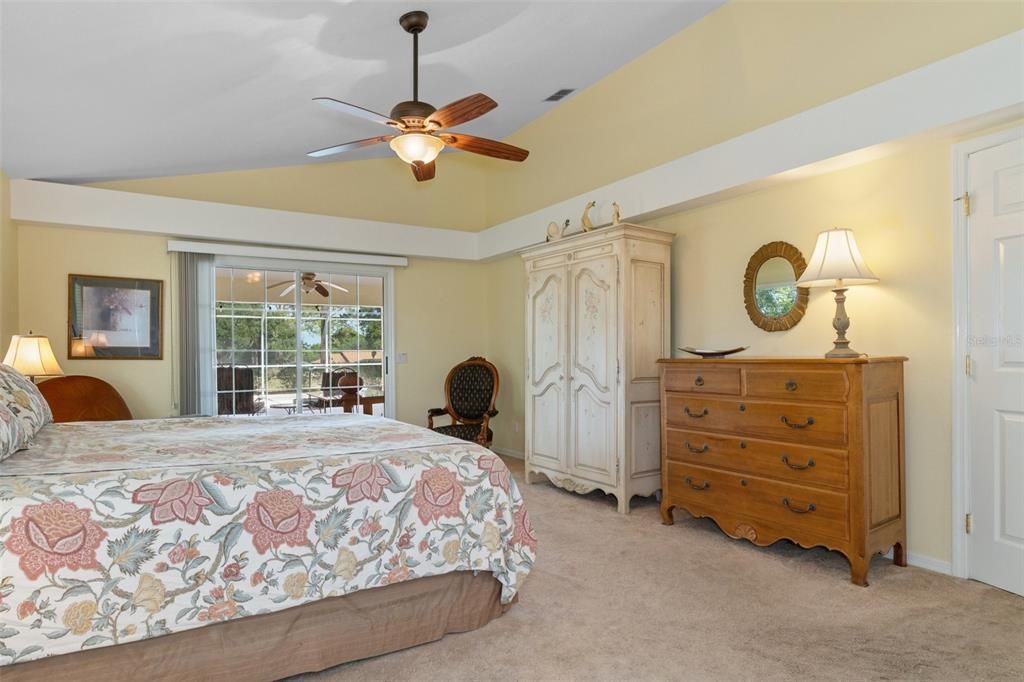 View of bedroom from bath entry, across room to sliding doors that lead to the lanai and pool.