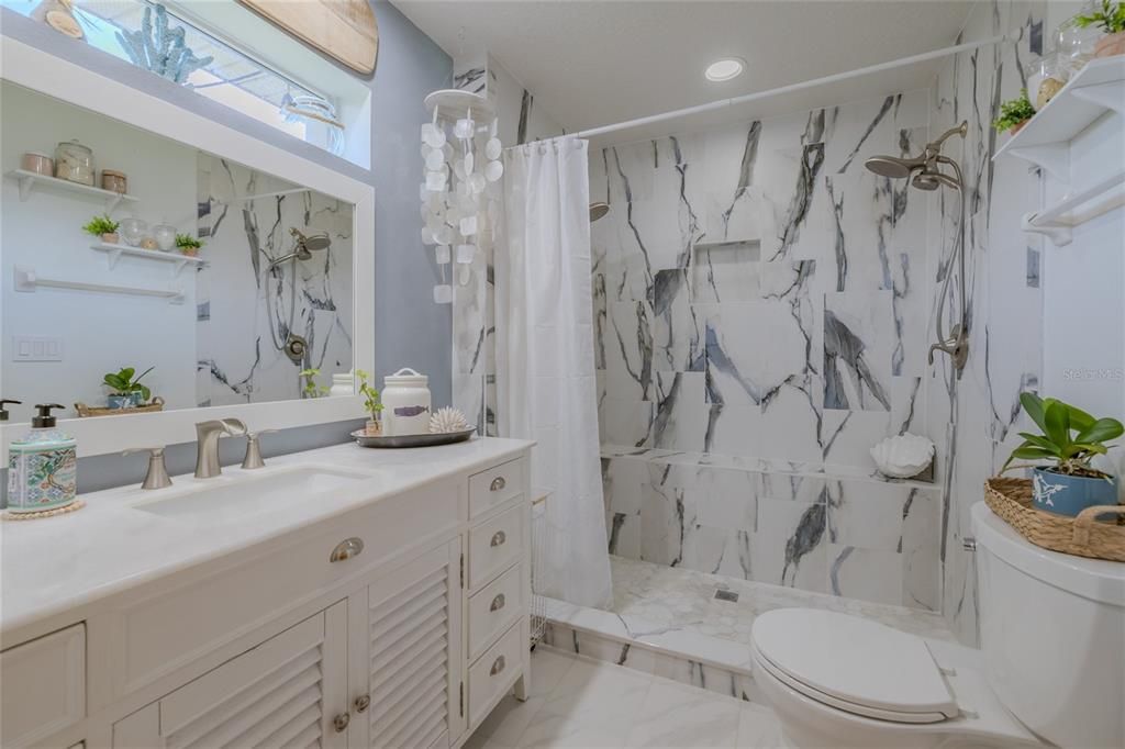 Newly updated primary bathroom with dual showerhead and seat