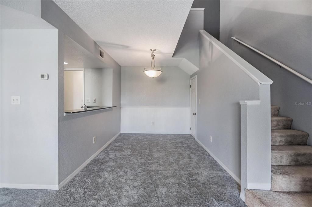 Dining room with stylish wainscoting on back wall and stairs up to loft bedroom.