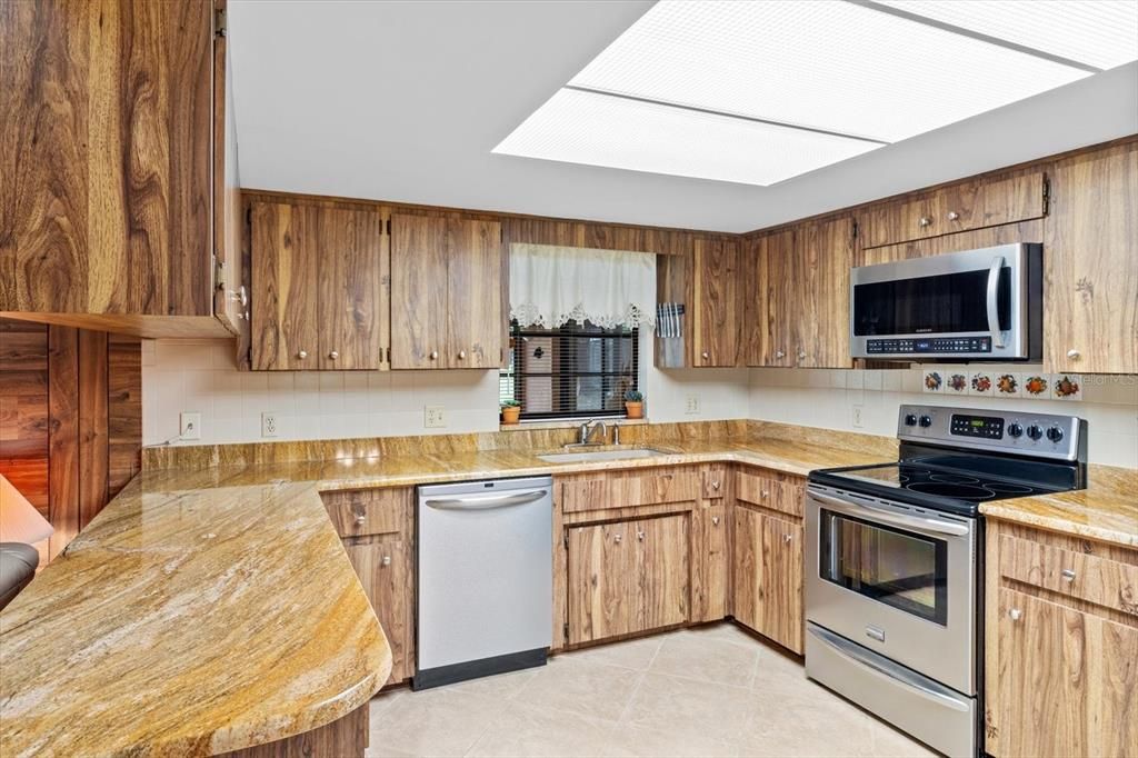 Kitchen Features Mid Century Modern Wood Style Laminate Cabinets w/ Granite Countertops, Stainless Steel Appliances, Dual Basin Sink, Tiled Backsplash & Recessed Lighting