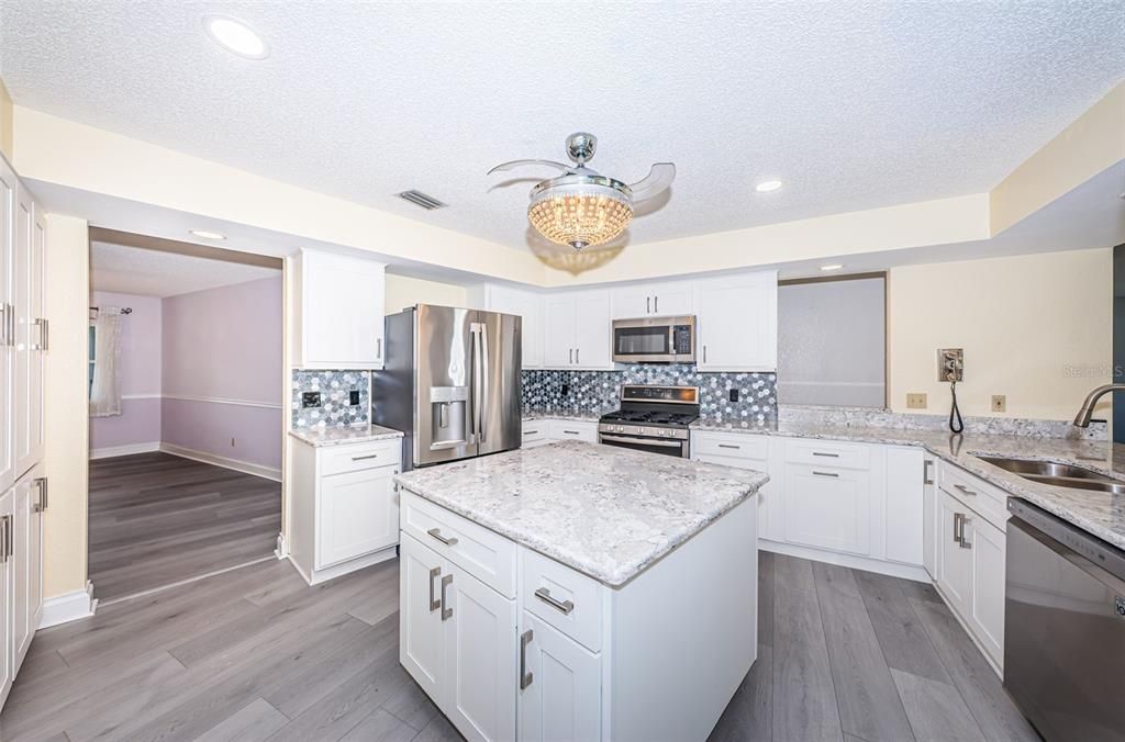 Beautifully renovated kitchen with island, breakfast bar, gas stove, quartz countertops, and stainless steel appliances