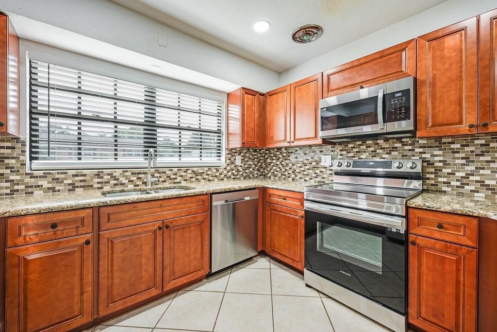 Your comfortable kitchen features easy care ceramic tile floors set on a diagonal complimentary to the STAINLESS STEEL APPLIANCES, decorative backsplash, and stylish cabinetry.