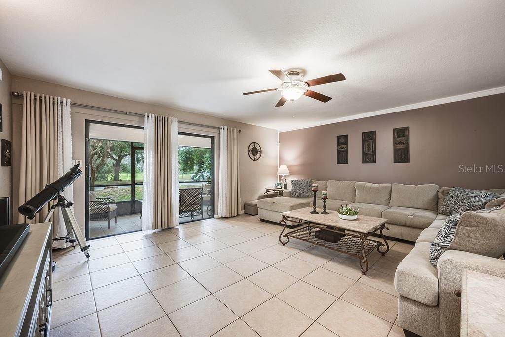 The generous living room has oversized sliding glass doors that open up to a large SCREENED LANAI with additional storage and a view of the park across the street.