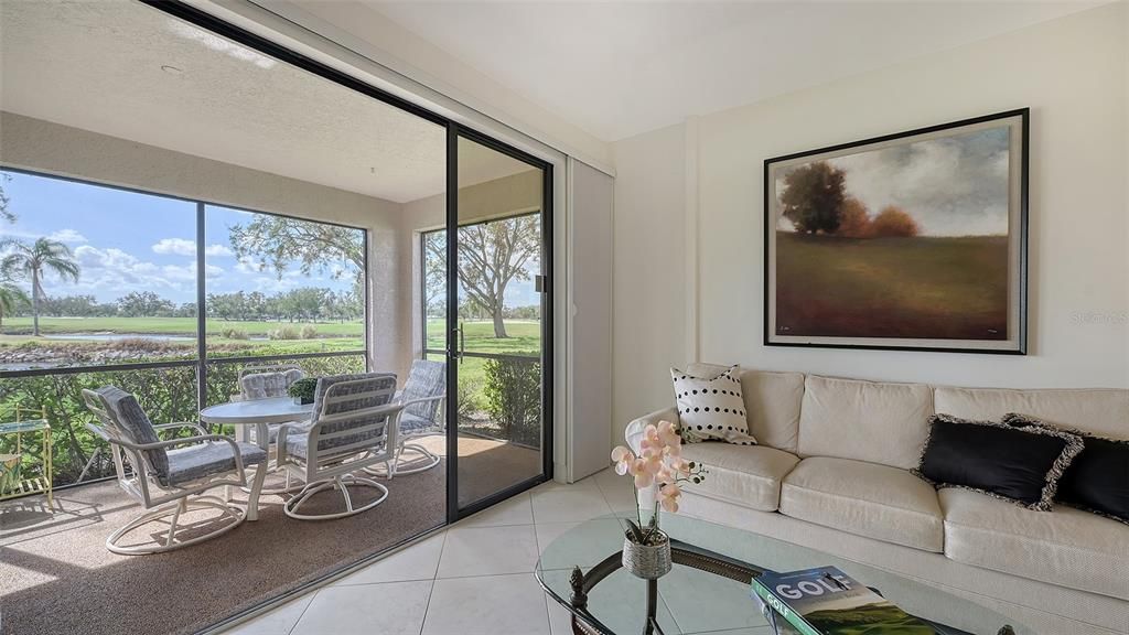 Expansive wall of sliders opening to a covered and screened lanai with water & golf course views