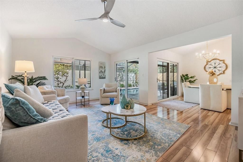 Enter through open living room with vaulted ceilings, beautiful floors, and many windows and sliders for a bright spacious and inviting atmosphere