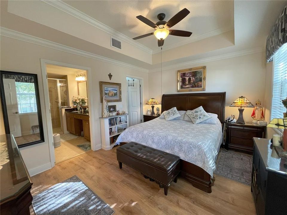 Primary suite features tray ceiling, plank-style flooring