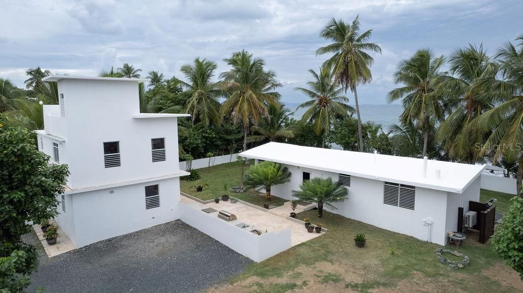 The one story structure is the main house with the front door between the shrubs