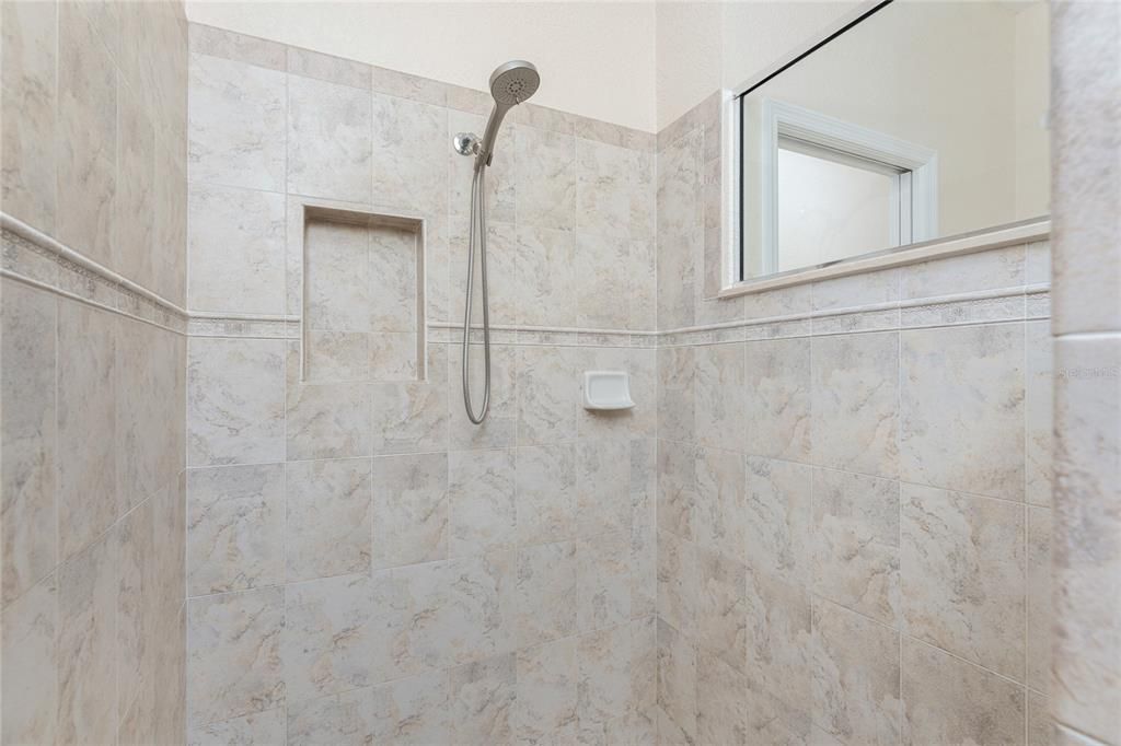 Owner walk-in shower with transom window, accent listello & shampoo niche.