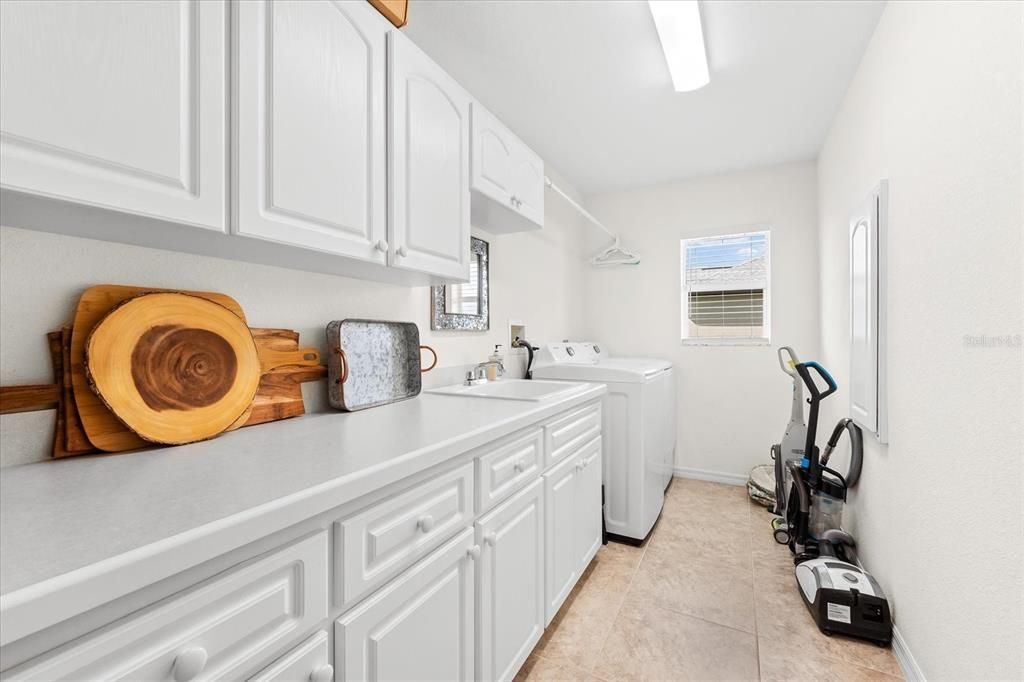 Large Indoor Laundry Featuring Utility Sink and Cabinetry