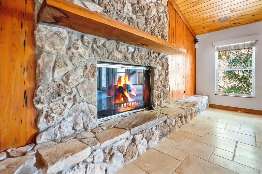 A cozy fireplace framed by rustic stone and rich wood brings warmth and charm to the room.