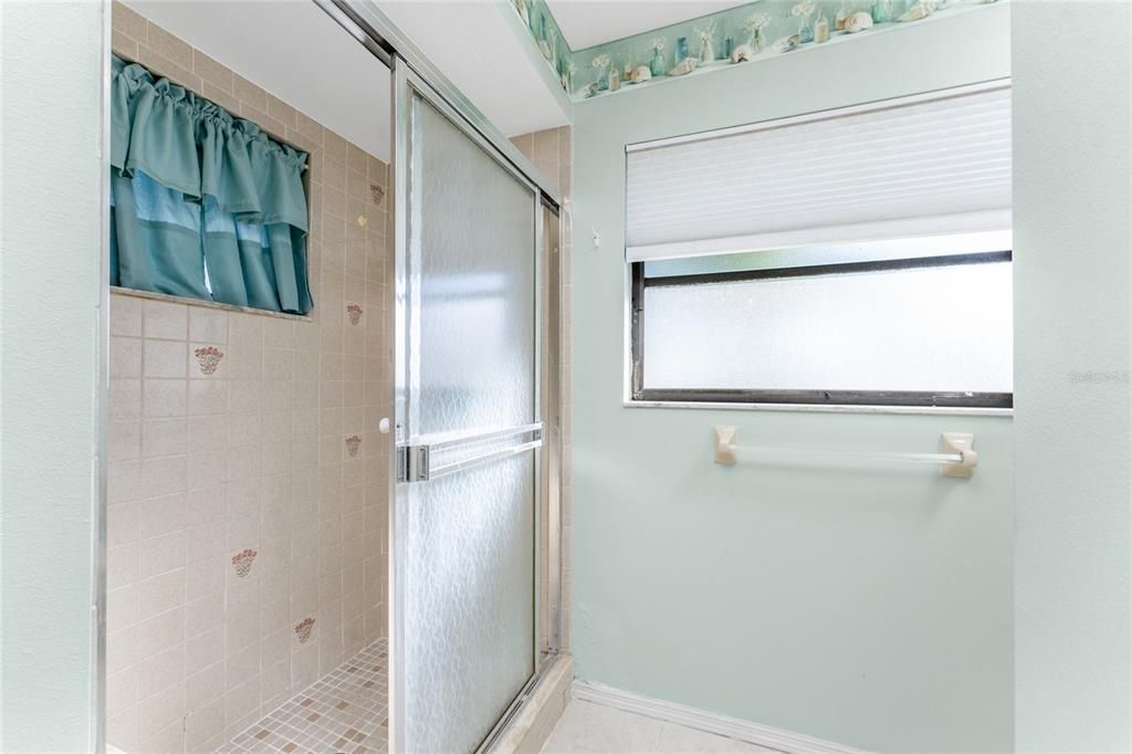 The bathroom has a step in shower with a sliding door.