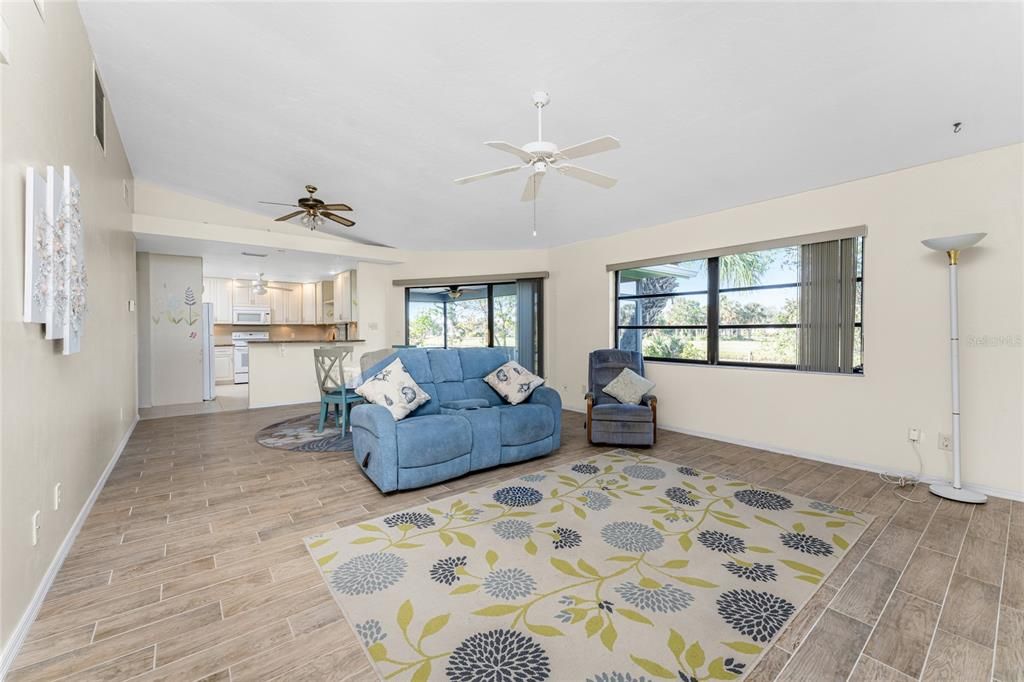 The living room has a cathedral ceiling, a ceiling fan and large window for natural light.