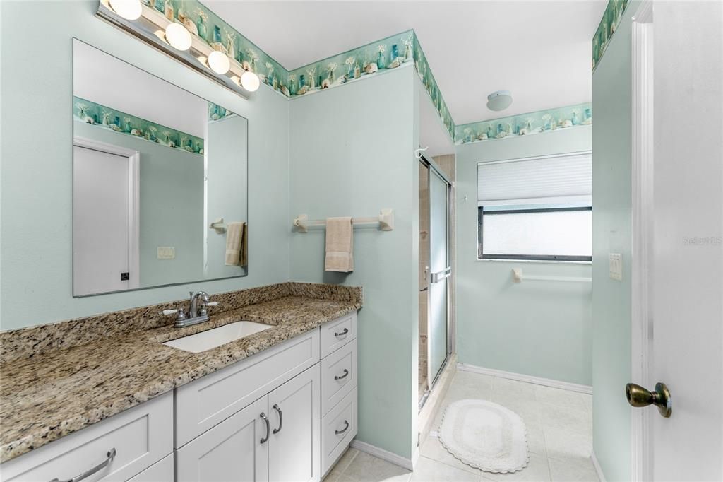 The master bathroom has a large updated vanity with a granite counter top.