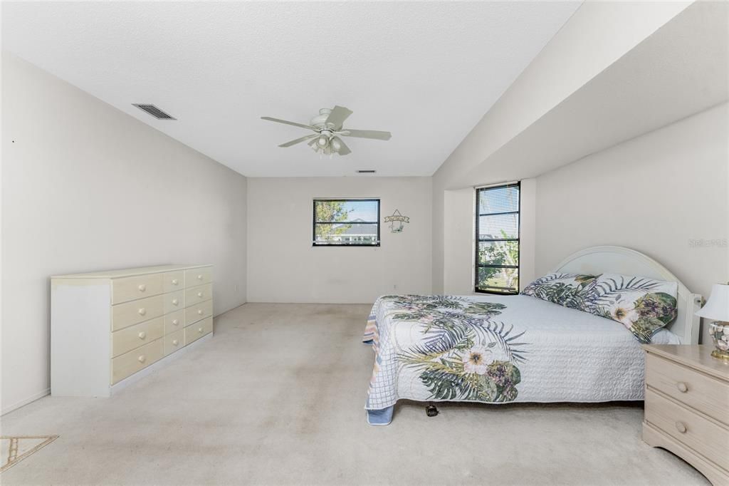 The master bedroom has carpeted flooring and a ceiling fan.