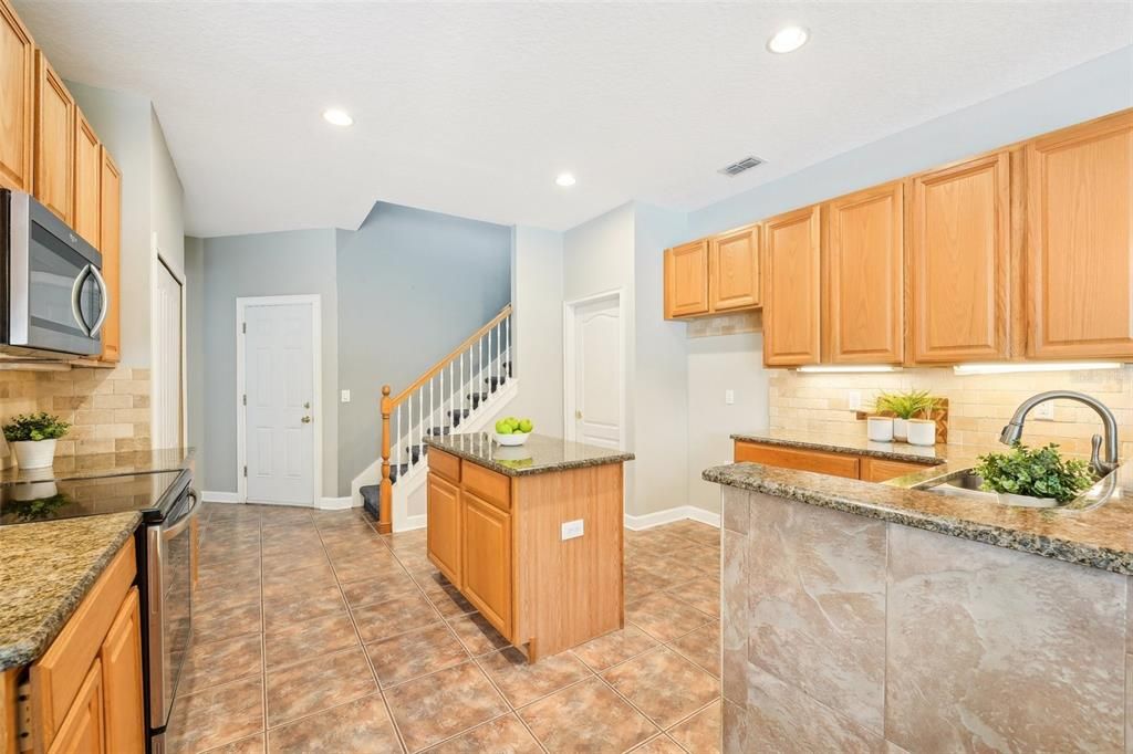 Under cabinet lighting, granite counters, wood cabinets, closet pantry & island with extra storage.