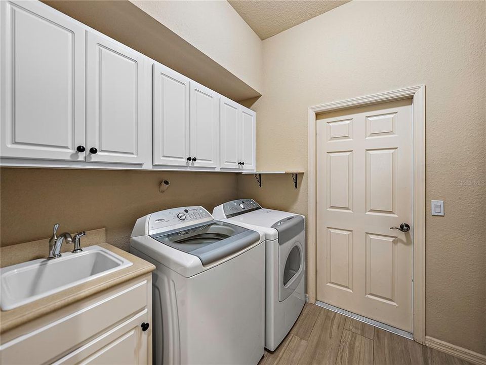 Laundry room (washer and dryer convey) with utility sink and cabinets for storage