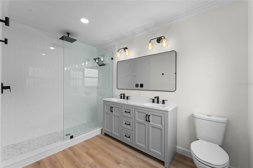 Primary bathroom features a walk-in shower with floor to ceiling tile and a double sink vanity