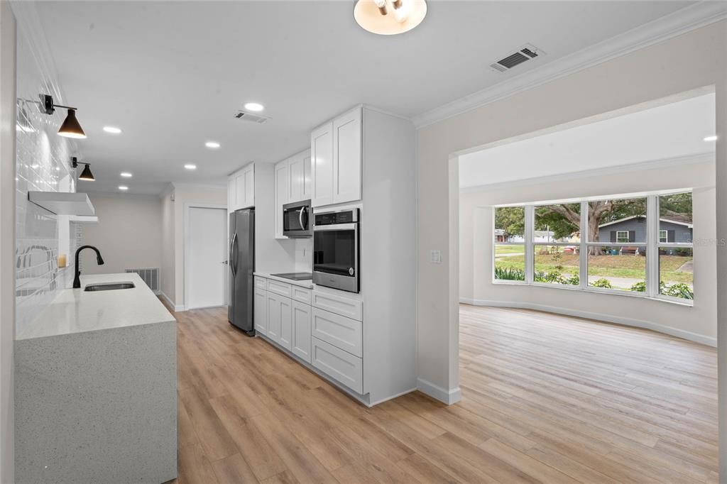 Open spacious floor plan with a kitchen that features shaker cabinets, quartz counters, built in oven, and an induction cooktop