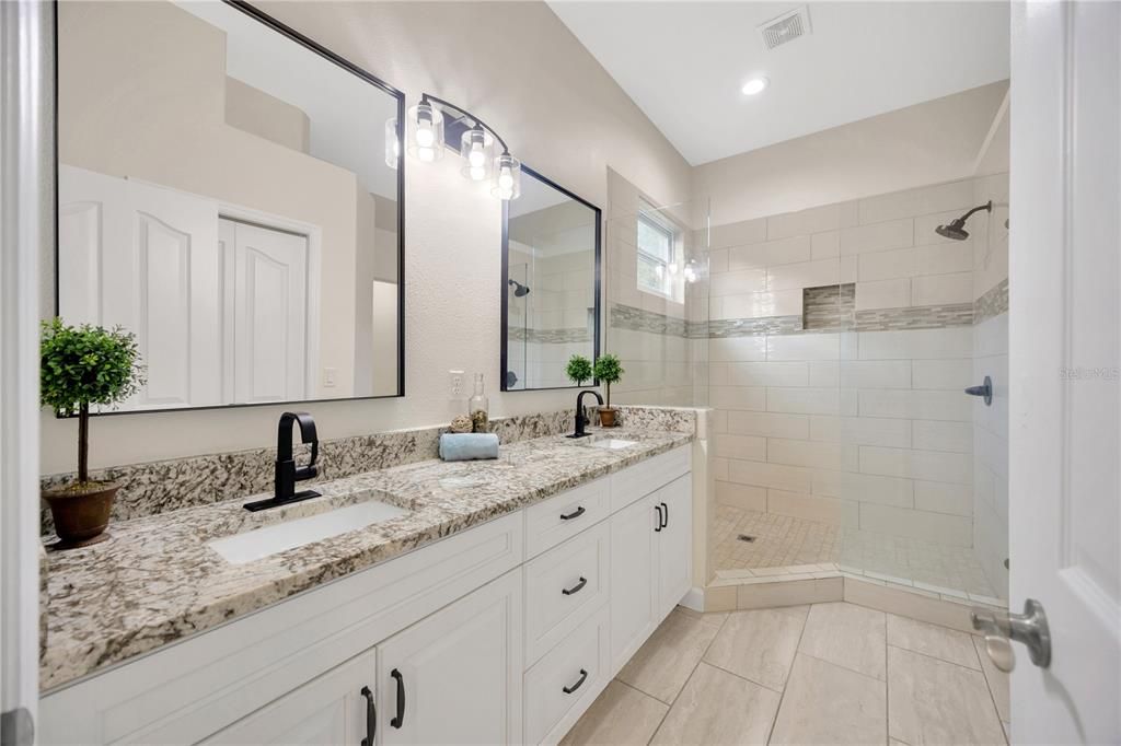 Primary bathroom with dual sinks, seamless glass shower, and walk in closet!