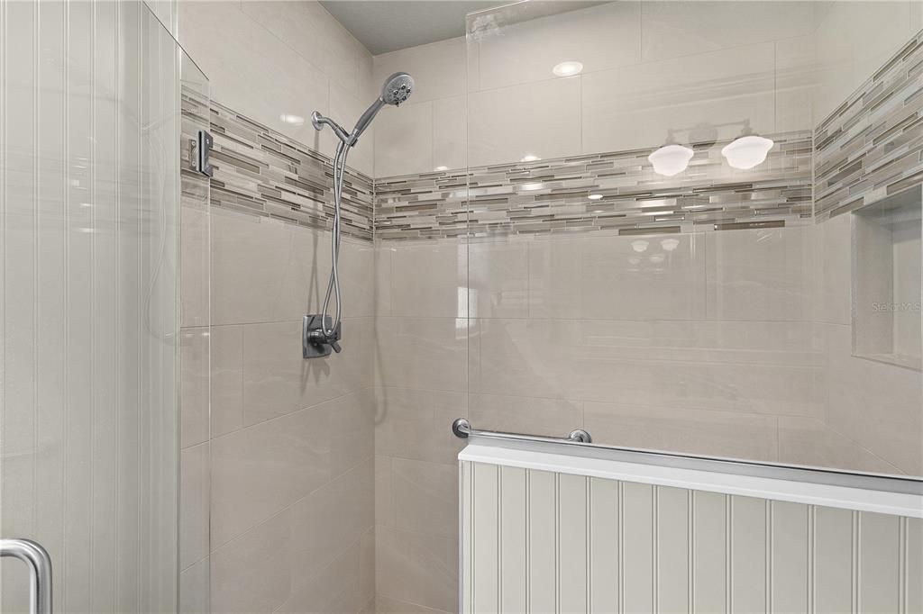 LOVELY TILED SHOWER WITH FRAMELESS GLASS DOOR.