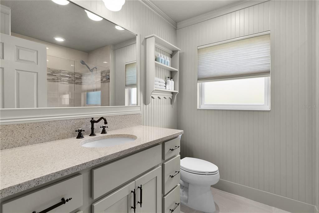 GUEST BATH WITH QUARTZ COUNTERS AND CUSTOM FRAMED MIRROR.