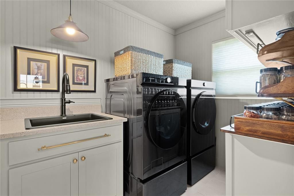 WASHER AND DRYER ON PEDESTALS THAT DO CONVEY WITH THE HOME.  MORE CABINETS SPACE AND SHELVING ON THE RIGHT.