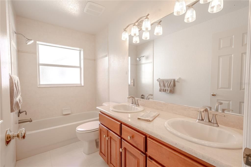 The 2nd bathroom features a tub with shower, a dual sink, mirrored solid wood vanity with storage and down-light fixtures.