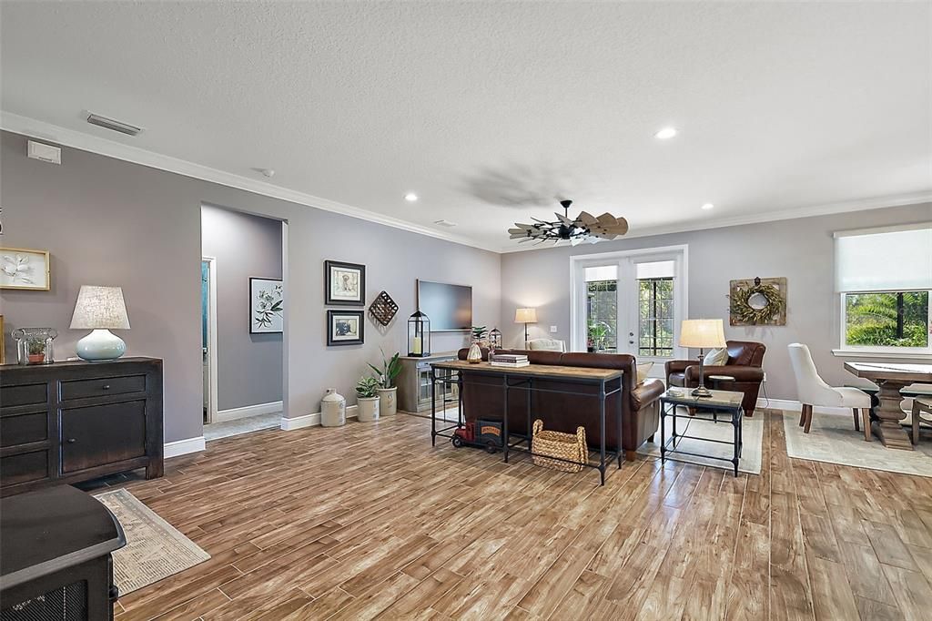 Living room opens to the lanai and pool via double French doors. Secondary bedrooms to the left.