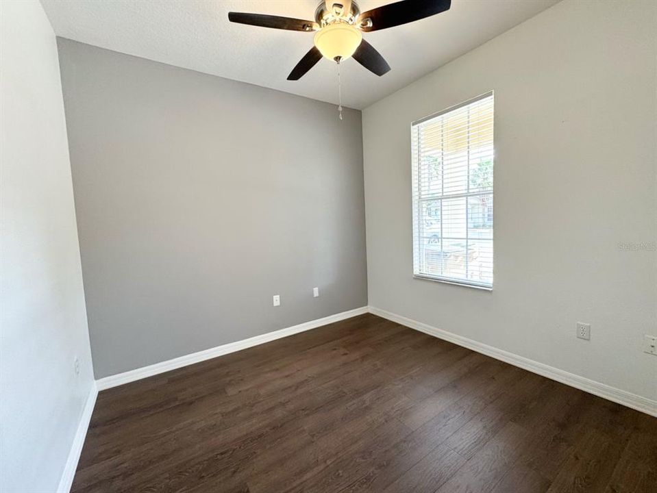 Downstairs Bedroom with new vinyl flooring, fan, and blind