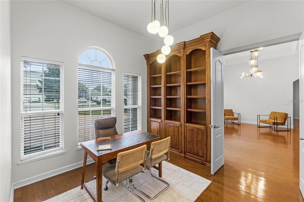 Office with Cherry hardwood floors, french doors for privacy and built-in desk with granite top located on the wall.