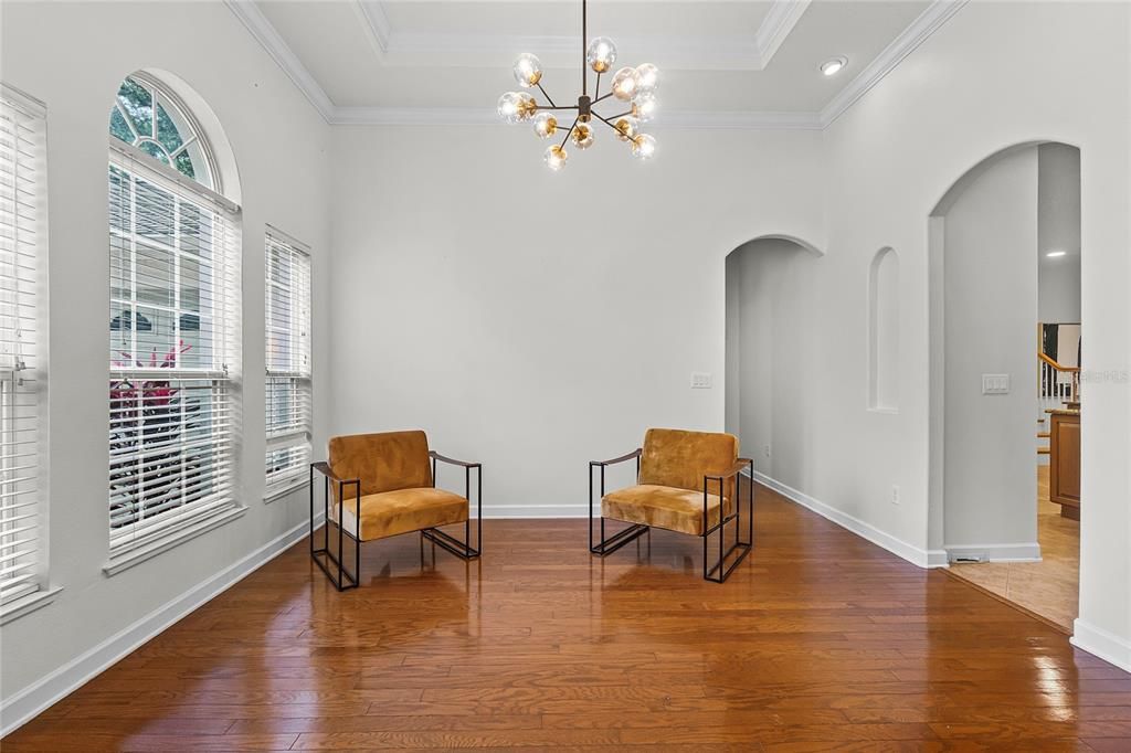 DINING ROOM WITH TRAY CEILING, CHERRY WOOD FLOORS & LARGE WINDOWS.