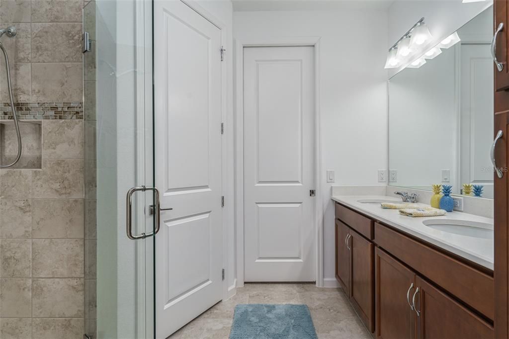 Primary bathroom with dual sinks, quartz counter top, linen closet to the right of sink. Large walk in closet.