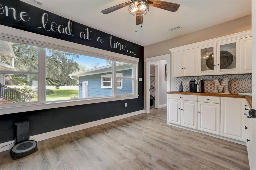 Huge laundry room in main home with door opening to Grooms area and putting green located in front of the picture window