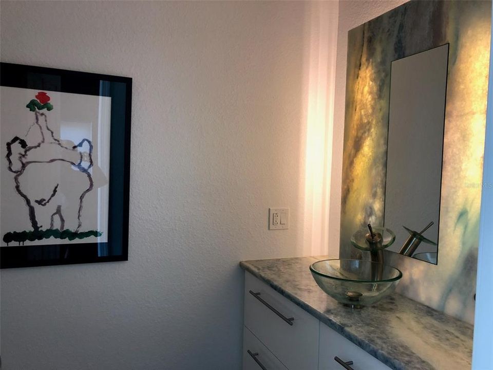 Hall Bathroom featuring a calcite countertop and custom lighted mirror wall panel.  The countertop, mirrored wall panel, sink and floating cabinet were preserved during the remediation.