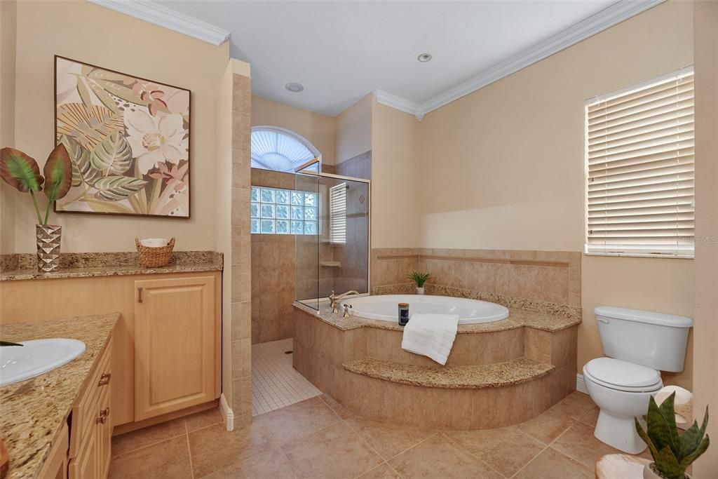 The soaking tub is set into a granite surround and the shower has no door and seamless glass panels.