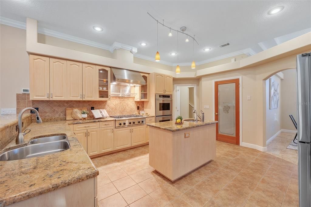 Chef-inspired kitchen is a culinary dream, equipped with a Thermador 6-burner gas cooktop, a sleek stainless steel hood with dual heat lamps, and a double convection oven integrated into the cabinetry.