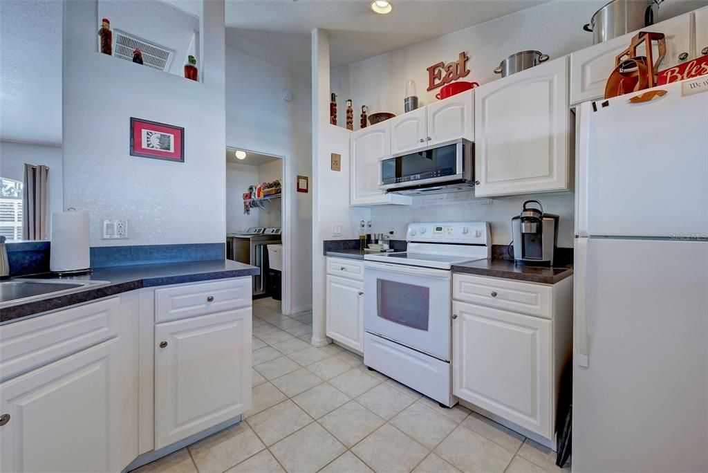 The vaulted ceiling and white cabinets enhance the size of the kitchen and the laundry room is conveniently located across the hallway.