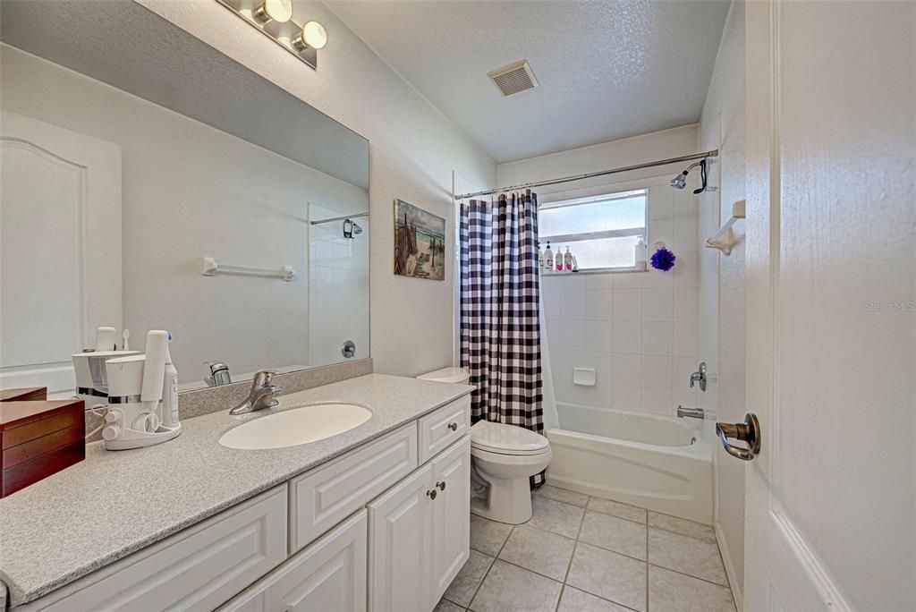 The guest bathroom has a large counter top and a shower bathtub combination.