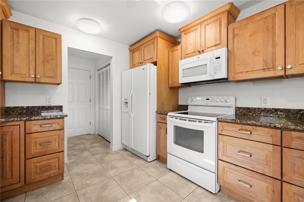 ALL APPLIANCES REMAIN, INCLUDING THE WASHER AND DRYER. VIEW OF THE KITCHEN TOWARDS THE LAUNDRY ROOM AND GARAGE