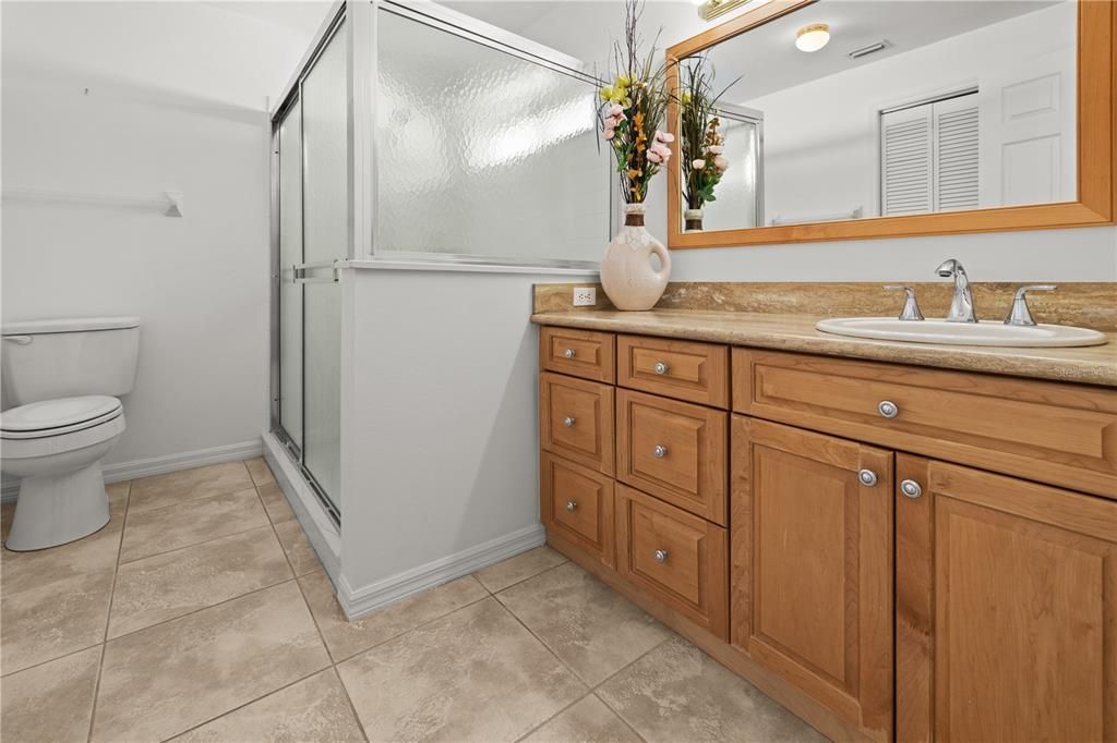 THE PRIMARY BATHROOM HAS TILE FLOOR AND LARGE SINGLE SINK VANITY