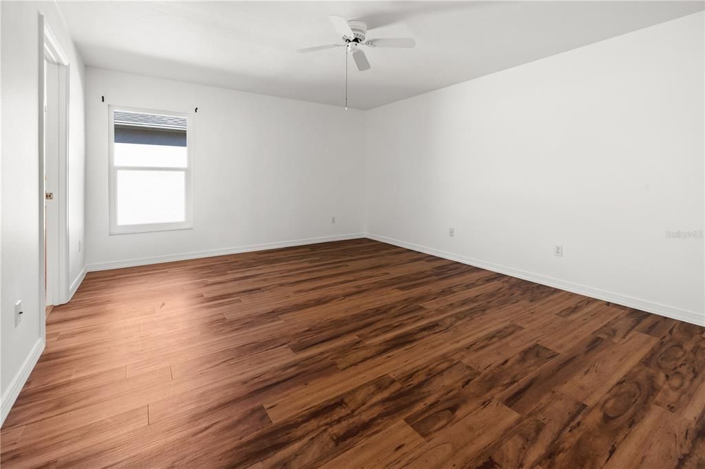 THE PRIMARY BEDROOM HAS LAMINATE FLOORING AND A WALK-IN CLOSET