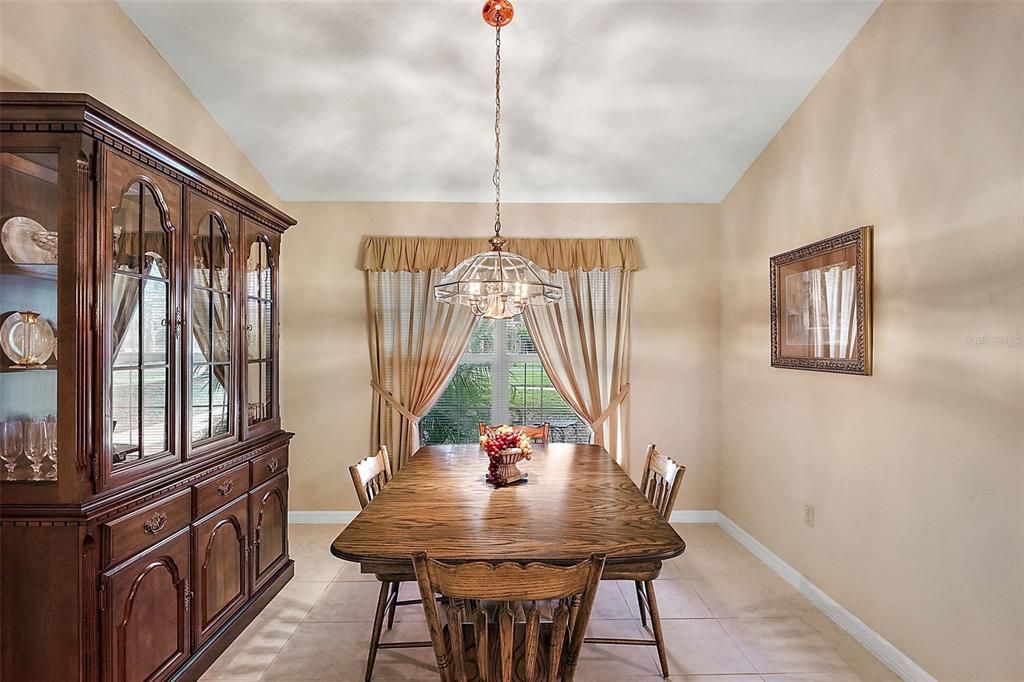 Formal dining room with vaulted ceiling and tile flooring.