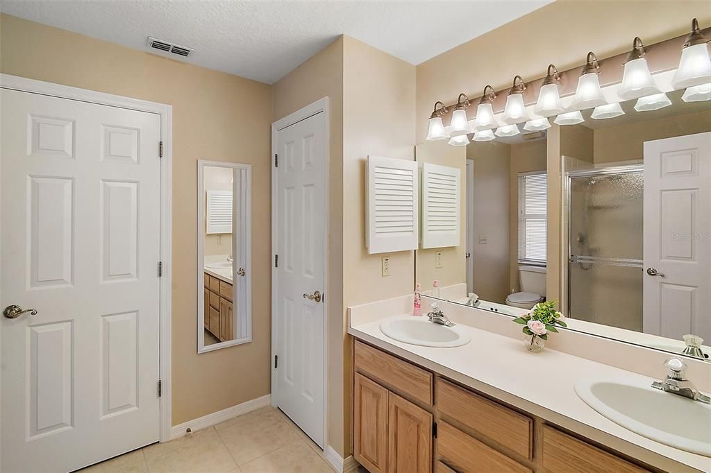 Primary bath with dual sinks, linen closet, and walk in closet