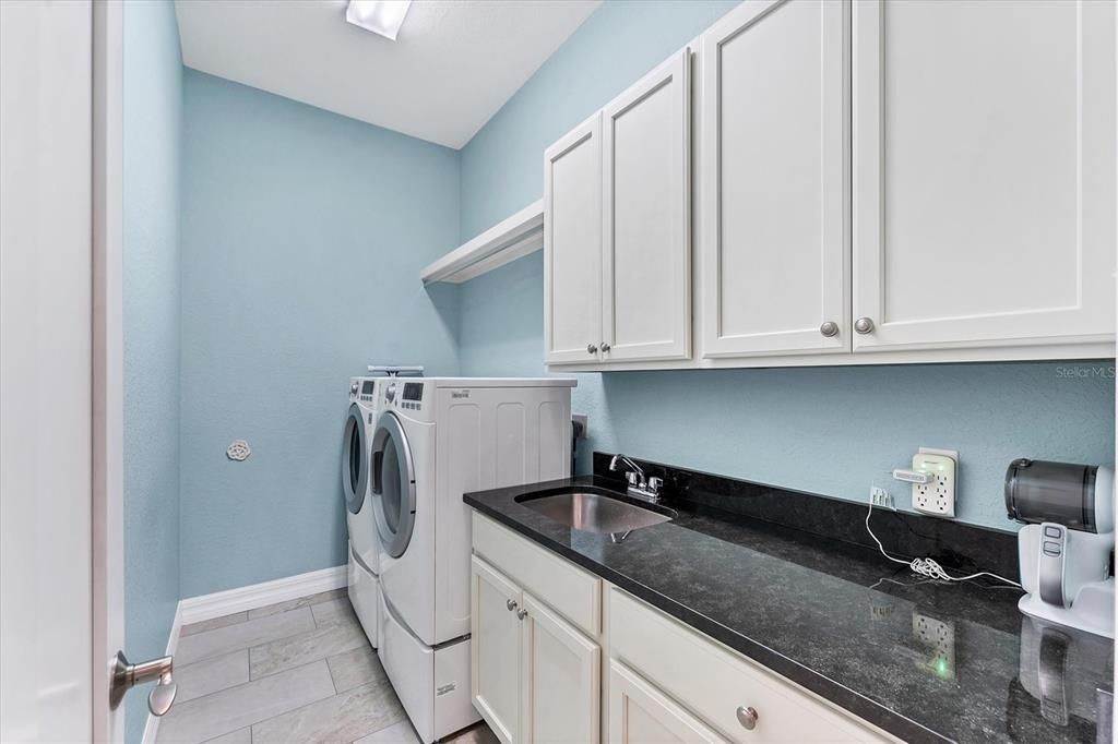 Separate laundry room with sink, counter and cabinets.