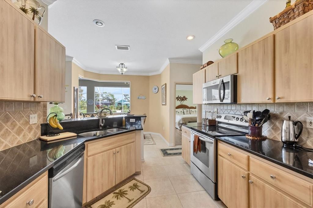 Kitchen is highlighted with stainless appliances, granite & a tiled backsplash